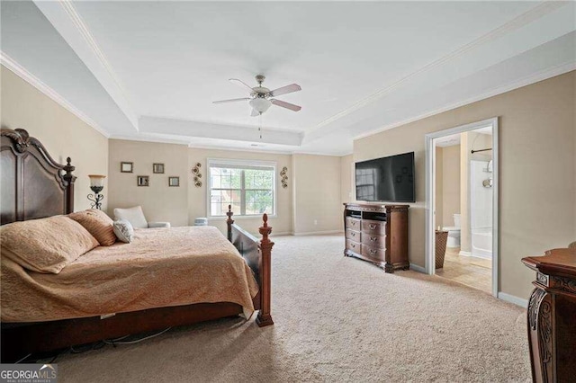 carpeted bedroom featuring ceiling fan, a raised ceiling, ensuite bath, and ornamental molding