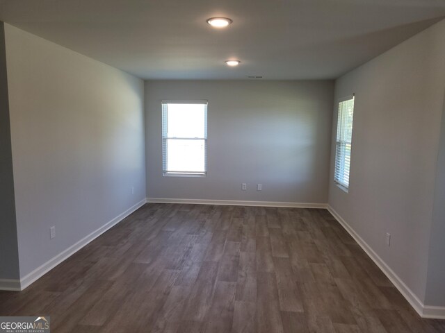 empty room with dark hardwood / wood-style flooring and a healthy amount of sunlight