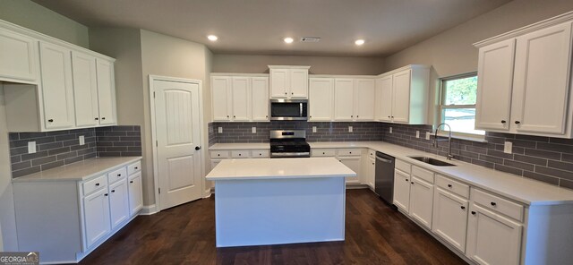 kitchen featuring appliances with stainless steel finishes, a kitchen island, sink, dark hardwood / wood-style floors, and white cabinetry