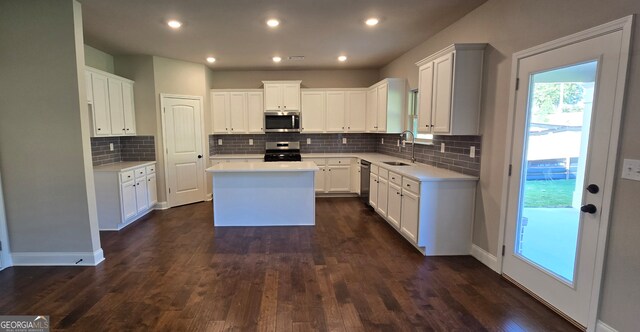 kitchen featuring appliances with stainless steel finishes, white cabinetry, a kitchen island, and dark hardwood / wood-style floors