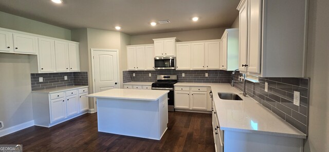 kitchen with white cabinetry, sink, dark wood-type flooring, stainless steel appliances, and a kitchen island