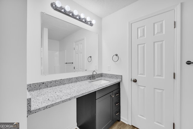 bathroom featuring hardwood / wood-style flooring, vanity, and a textured ceiling