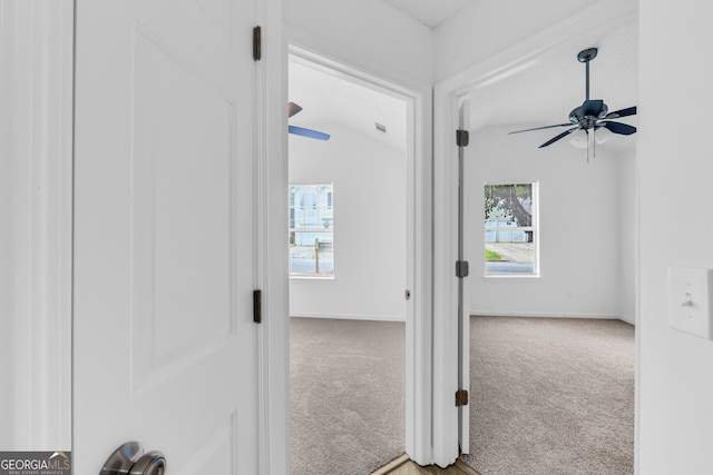 corridor featuring vaulted ceiling and carpet flooring