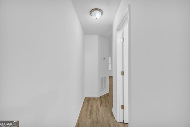 corridor featuring light hardwood / wood-style floors and a textured ceiling