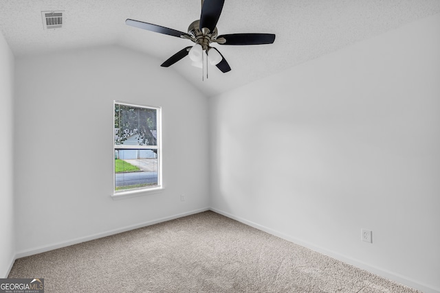 carpeted empty room featuring ceiling fan, vaulted ceiling, and a textured ceiling