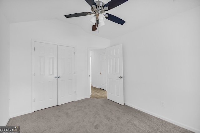 unfurnished bedroom with vaulted ceiling, light colored carpet, ceiling fan, and a closet