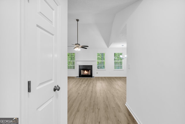 unfurnished living room with lofted ceiling, a premium fireplace, a textured ceiling, and light wood-type flooring