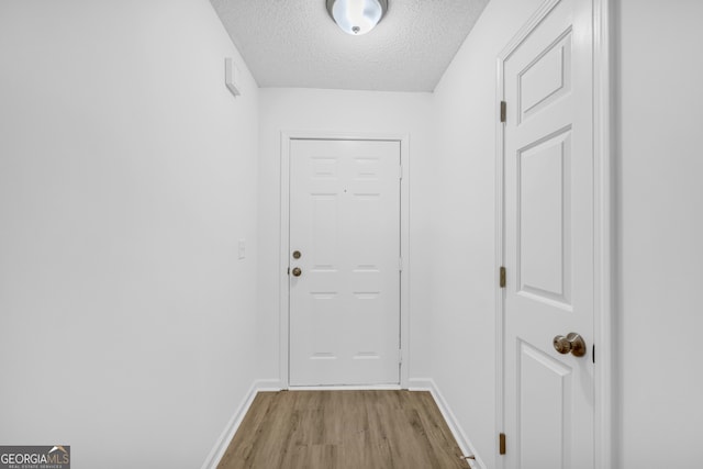 doorway with a textured ceiling and light hardwood / wood-style flooring