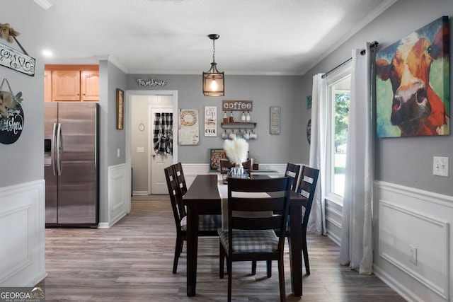 dining room with ornamental molding, light wood-type flooring, and a textured ceiling