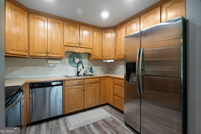 kitchen with stainless steel appliances, light hardwood / wood-style floors, decorative backsplash, and sink