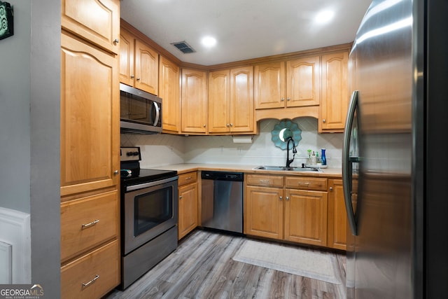 kitchen featuring light wood-type flooring, sink, stainless steel appliances, and tasteful backsplash