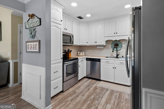 clothes washing area featuring washer and clothes dryer, a textured ceiling, and light hardwood / wood-style flooring