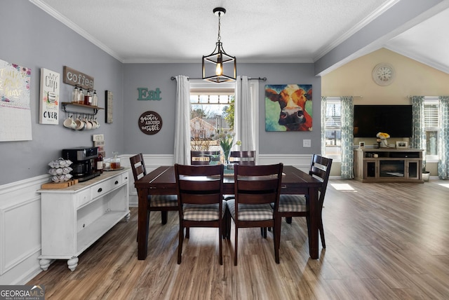 dining area featuring a textured ceiling, wainscoting, wood finished floors, and crown molding