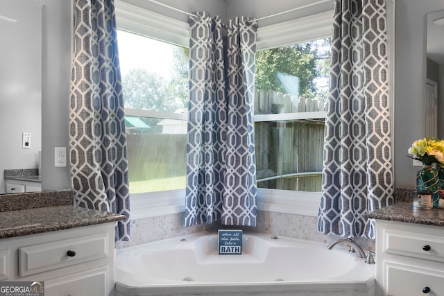 bathroom with a tub to relax in, vanity, and a healthy amount of sunlight