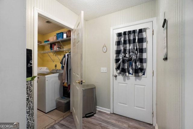 laundry room featuring a textured ceiling, laundry area, independent washer and dryer, and wood finished floors