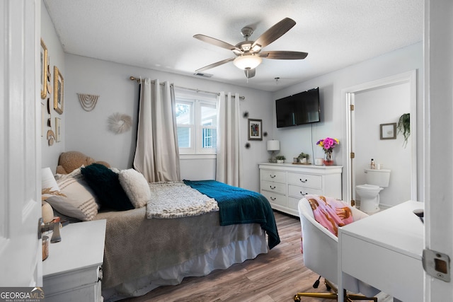 bedroom with ceiling fan, hardwood / wood-style flooring, ensuite bath, and a textured ceiling