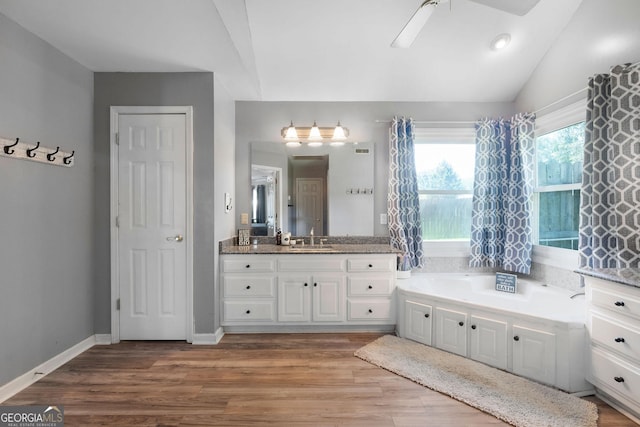 full bath with vanity, wood finished floors, baseboards, lofted ceiling, and a bath