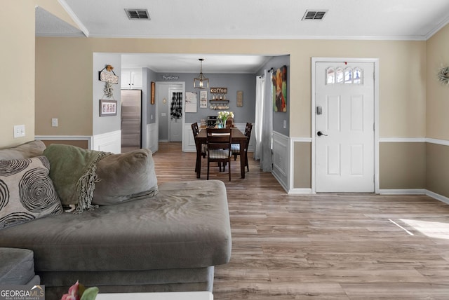 living room featuring ornamental molding, visible vents, and light wood-style flooring