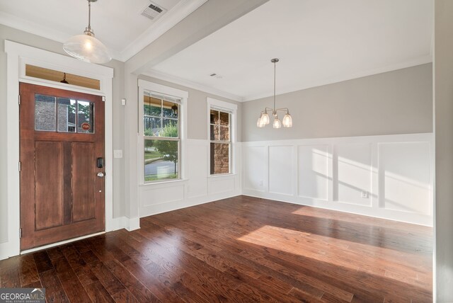 foyer entrance featuring a notable chandelier, dark hardwood / wood-style flooring, and ornamental molding