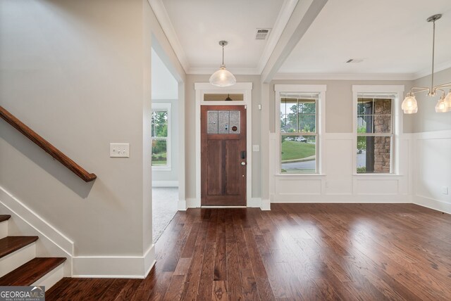 foyer entrance with dark hardwood / wood-style flooring, ornamental molding, and a wealth of natural light