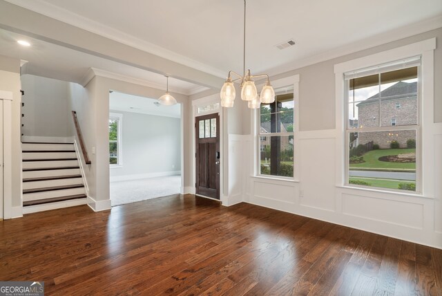 unfurnished dining area featuring dark hardwood / wood-style floors, a healthy amount of sunlight, an inviting chandelier, and crown molding