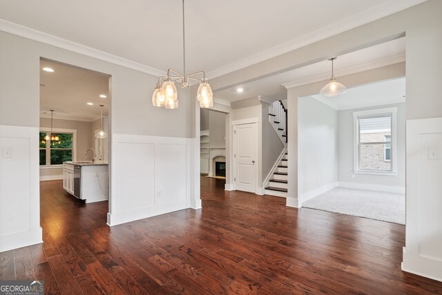 unfurnished dining area with dark hardwood / wood-style floors, a healthy amount of sunlight, an inviting chandelier, and crown molding