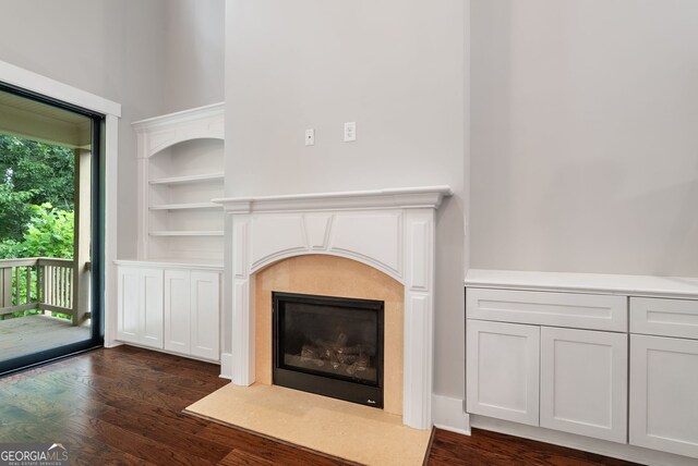 unfurnished living room with built in features and dark hardwood / wood-style flooring