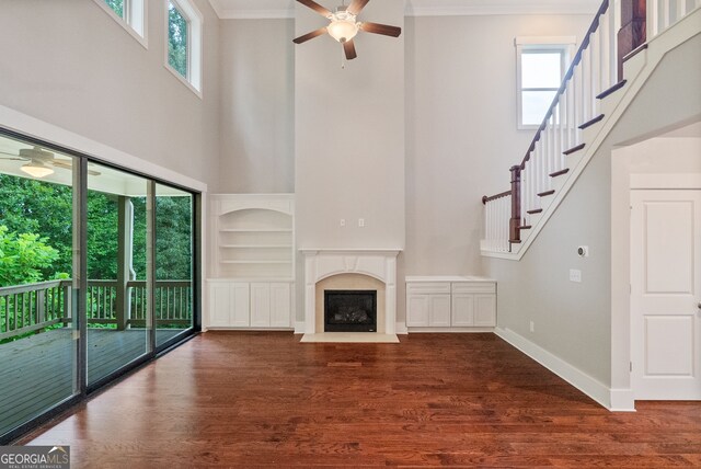 unfurnished living room with ceiling fan, a premium fireplace, hardwood / wood-style flooring, and a wealth of natural light