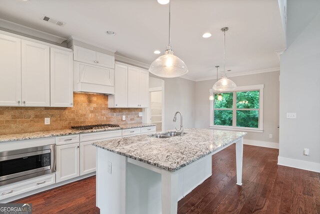 kitchen featuring dark hardwood / wood-style floors, appliances with stainless steel finishes, a center island with sink, tasteful backsplash, and a breakfast bar area