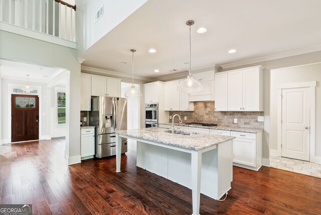 kitchen with stainless steel appliances, dark hardwood / wood-style floors, a kitchen island with sink, backsplash, and decorative light fixtures