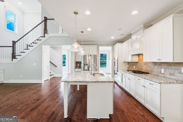 kitchen featuring appliances with stainless steel finishes, dark hardwood / wood-style flooring, ornamental molding, and a kitchen island with sink