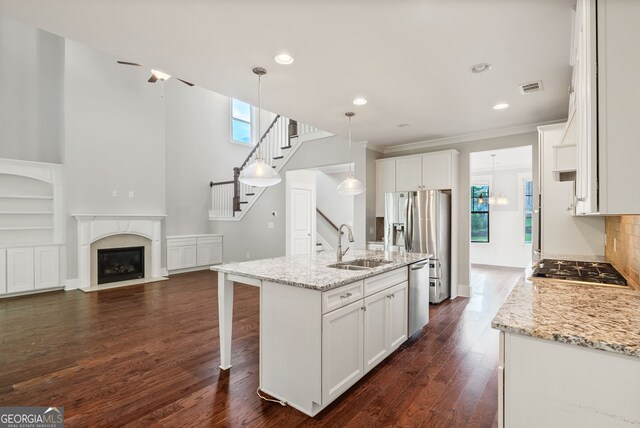 kitchen featuring dark hardwood / wood-style flooring, white cabinets, a center island with sink, backsplash, and sink