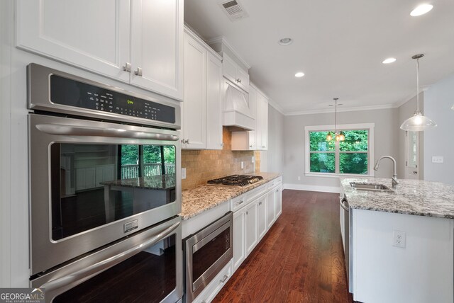 kitchen featuring dark wood-type flooring, stainless steel appliances, crown molding, sink, and backsplash