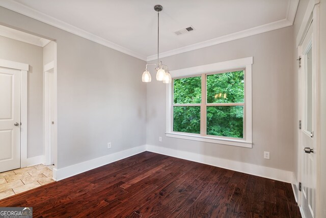 unfurnished dining area featuring hardwood / wood-style floors, crown molding, and a notable chandelier