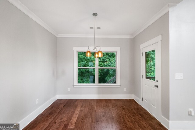 unfurnished dining area featuring ornamental molding, dark hardwood / wood-style floors, and an inviting chandelier