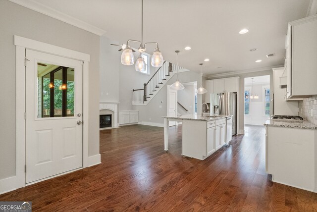 kitchen with tasteful backsplash, dark wood-type flooring, an island with sink, and white cabinetry