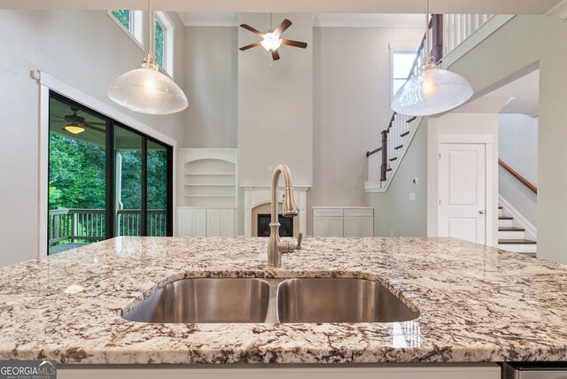 kitchen featuring built in shelves, ceiling fan, sink, ornamental molding, and decorative light fixtures