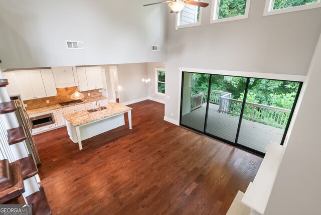 living room featuring ceiling fan, dark hardwood / wood-style flooring, a high ceiling, and a wealth of natural light