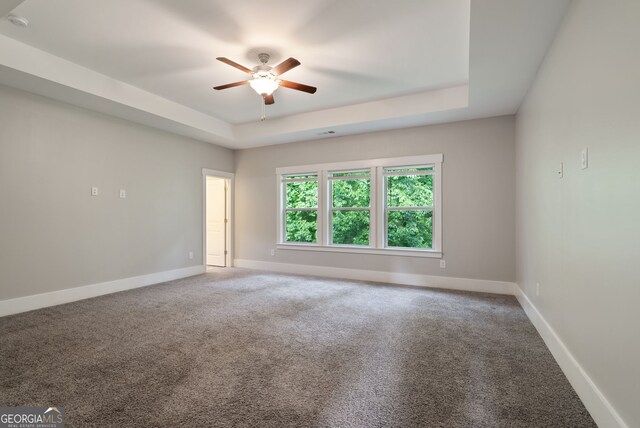 carpeted empty room featuring a tray ceiling and ceiling fan