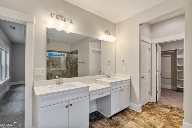 bathroom with a tile shower, dual vanity, and tile patterned flooring