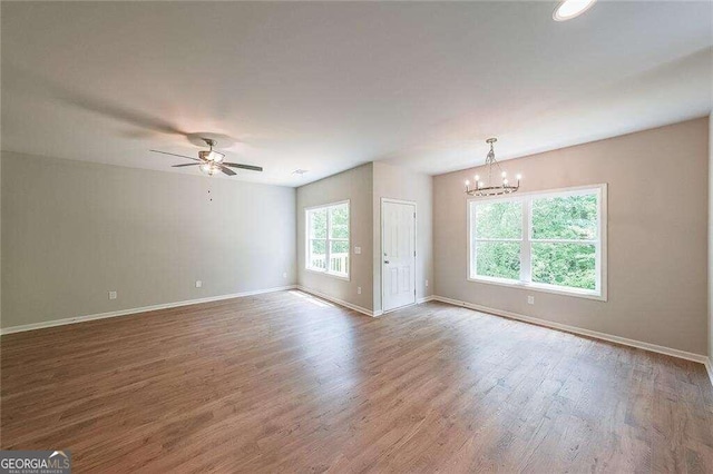 unfurnished room featuring ceiling fan with notable chandelier and hardwood / wood-style floors