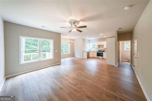 unfurnished living room with ceiling fan with notable chandelier, sink, and wood-type flooring