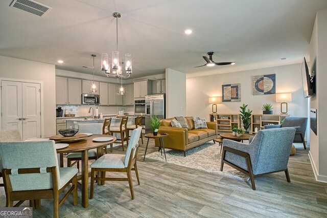 interior space with sink, light hardwood / wood-style flooring, and ceiling fan with notable chandelier