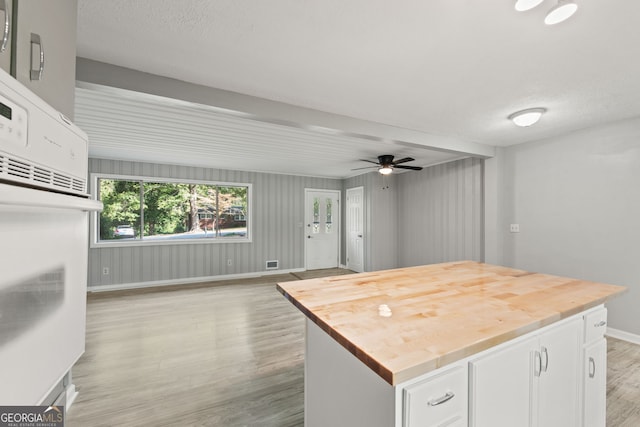 kitchen featuring white cabinets, ceiling fan, a textured ceiling, light hardwood / wood-style floors, and a center island