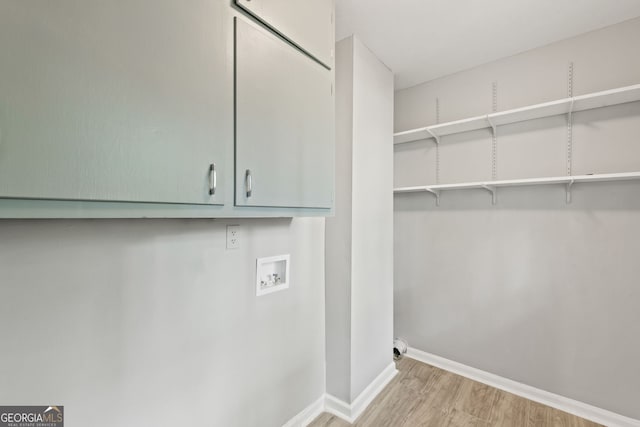 clothes washing area featuring washer hookup, light wood-type flooring, and cabinets