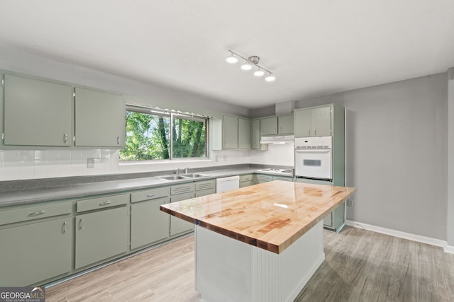 kitchen featuring a kitchen island, light wood-type flooring, butcher block counters, sink, and white appliances