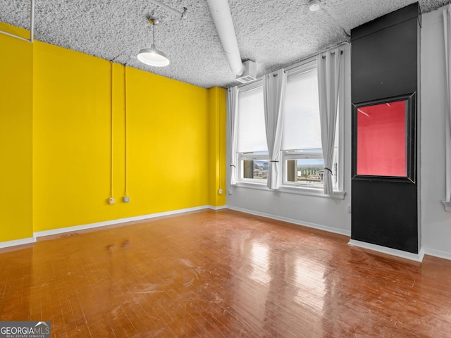 spare room with a textured ceiling and wood-type flooring