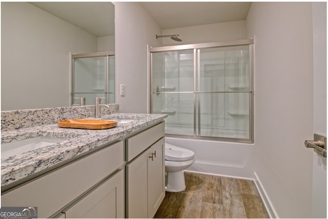 full bathroom with toilet, vanity, shower / bath combination with glass door, and wood-type flooring