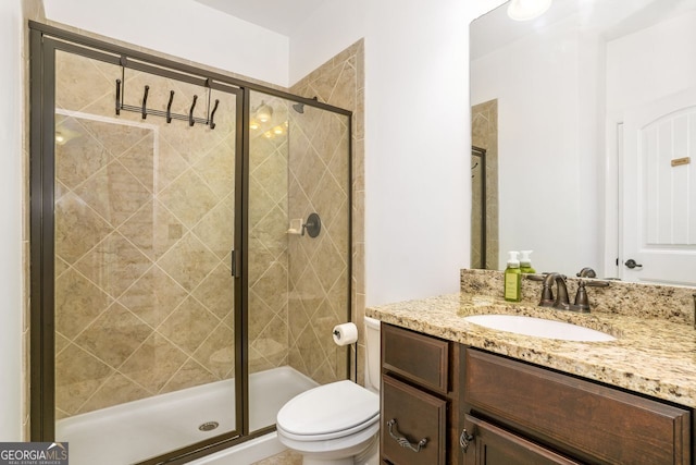 bathroom featuring a shower with shower door, toilet, and vanity