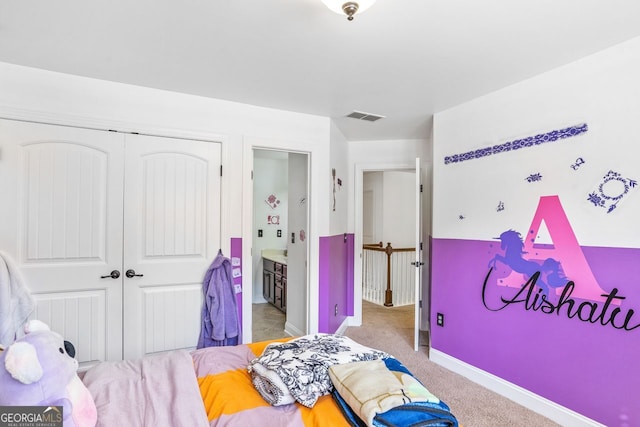 bedroom featuring a closet, light carpet, and ensuite bath